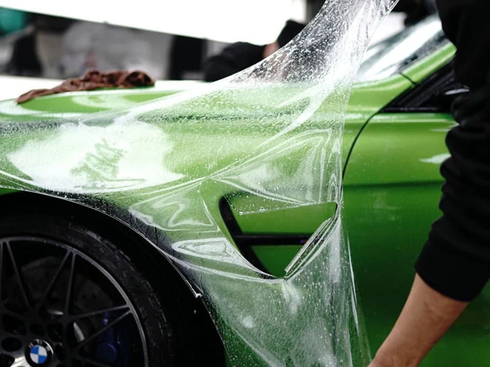Close-up of paint protection film being installed along a vehicle's front fender edge